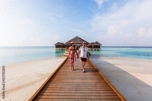 Adult couple walking on jetty in an island in the Maldives