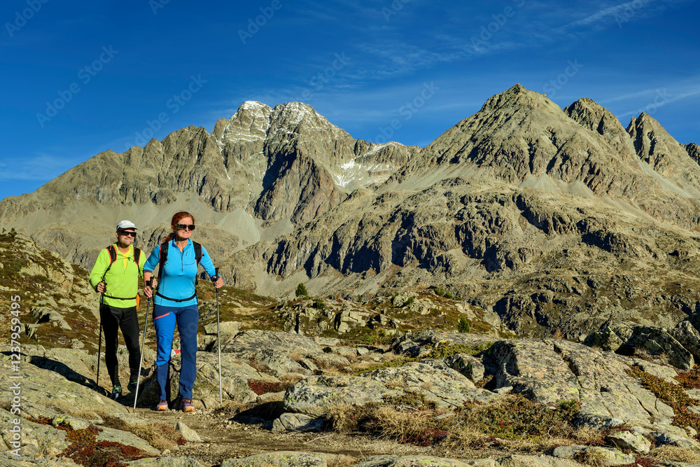 Man and woman hiking on Piz Julier mountain under blue sky Man and woman hiking on Piz Julier mountain under blue sky
