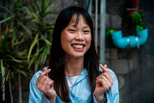 Young woman smiling and making a Korean finger heart gesture outdoors in Barcelona photo