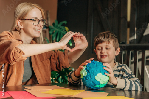 Mother making heart shape with son sculpting clay Earth at home photo