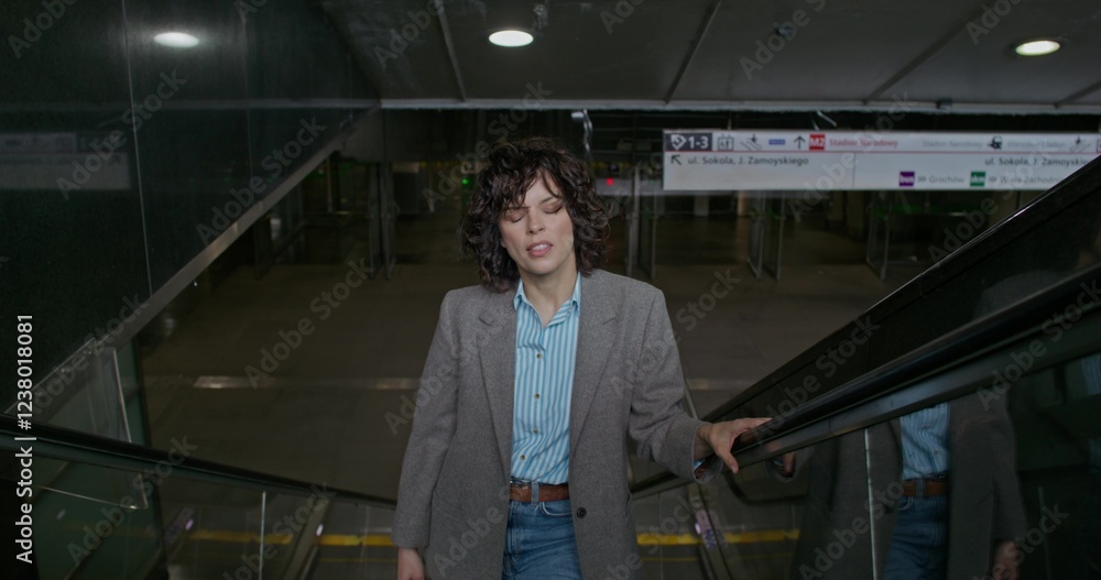 A woman in casual clothes walks up the escalator in the subway A woman in casual clothes walks up the escalator in the subway
