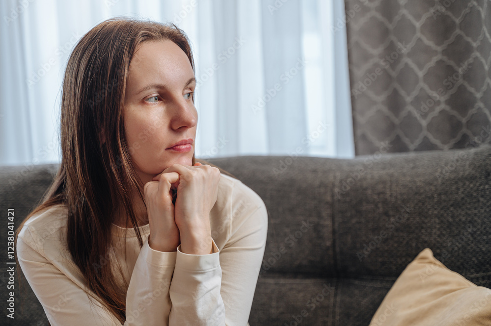 Woman sits alone, sad and depressed, touches her head in despair at home, struggles with depression and mental health issues Woman sits alone, sad and depressed, touches her head in despair at home, struggles with depression and mental health issues