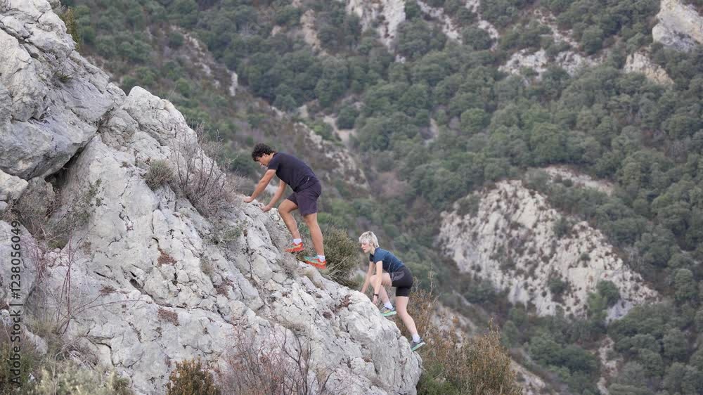 Two young climbers scaling a steep rocky mountain Two young climbers scaling a steep rocky mountain