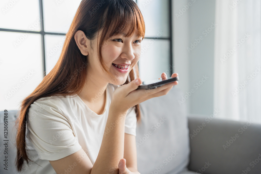 Asian woman holding smartphone near mouth talking with friend Asian woman holding smartphone near mouth talking with friend