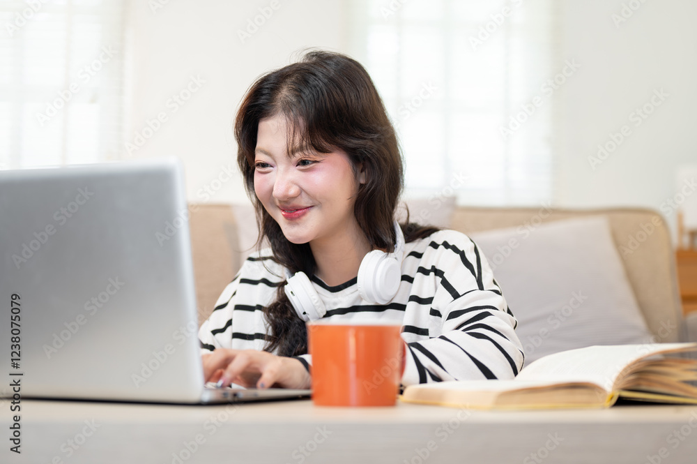 A cheerful young Asian female college student is enjoying browsing the internet on her laptop. A cheerful young Asian female college student is enjoying browsing the internet on her laptop.