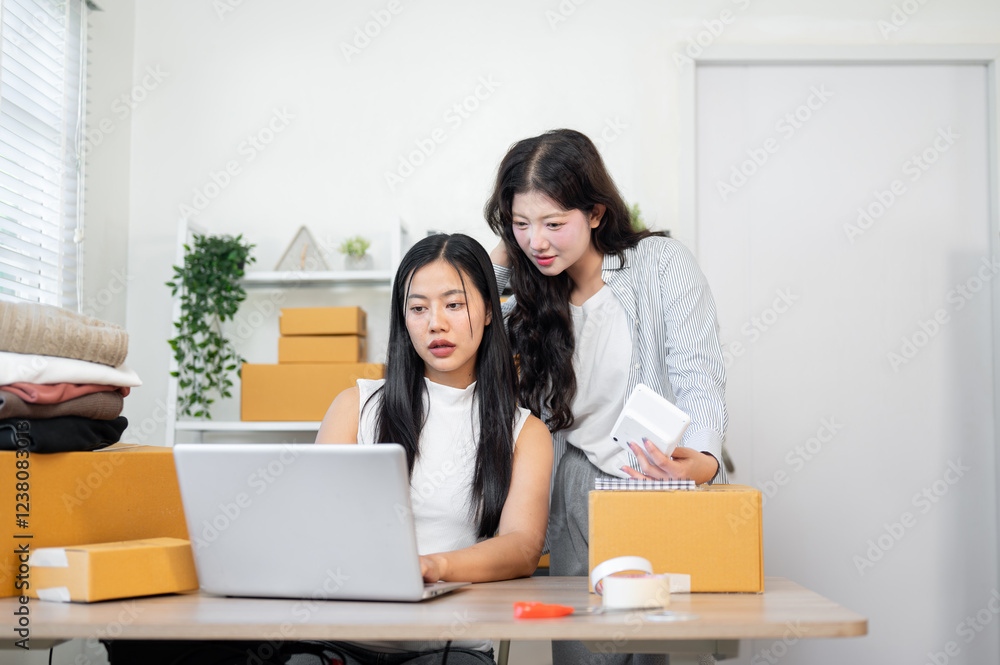 An Asian woman is showing e-commerce shipping orders on the website on a laptop to her colleague. An Asian woman is showing e-commerce shipping orders on the website on a laptop to her colleague.