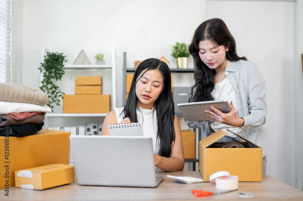 Two positive Asian female business partners are working in the office. Two positive Asian female business partners are working in the office.