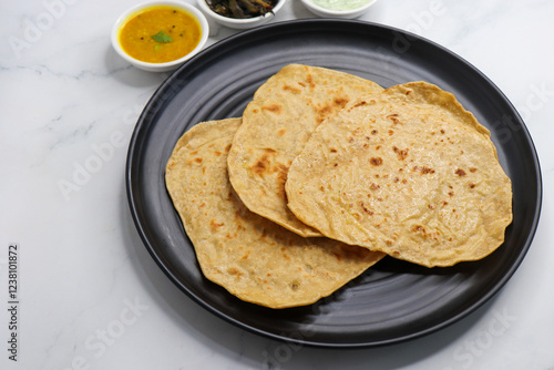 Roti and Sabzi. Indian vegetarian Thali includes bhindi fry, yellow daal tadka, cucumber raita, and chapati or tel paratha. Indian food is served in a plate or thali. Copy Space. healthy Veg Thali.  photo