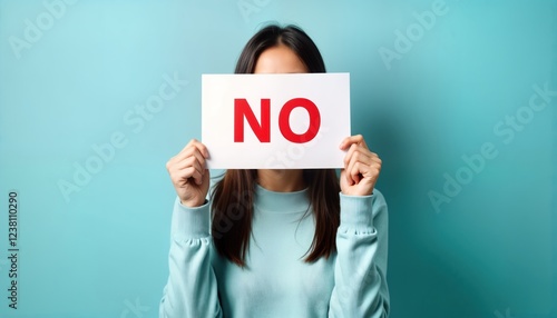 Woman holds sign saying NO. Refusal concept. Studio photo. Woman in light blue sweatshirt. Clear message. Photo for social media or activism. Ideal for education. Simple design. Strong visual. photo