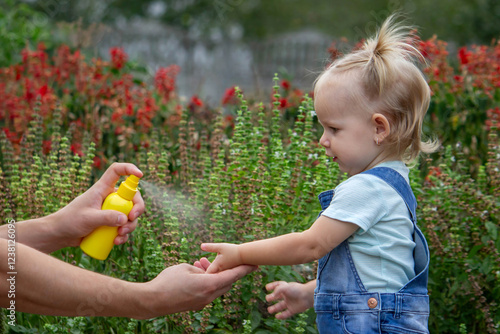 mother applies an aerosol insect spray to the child's body. Selective focus