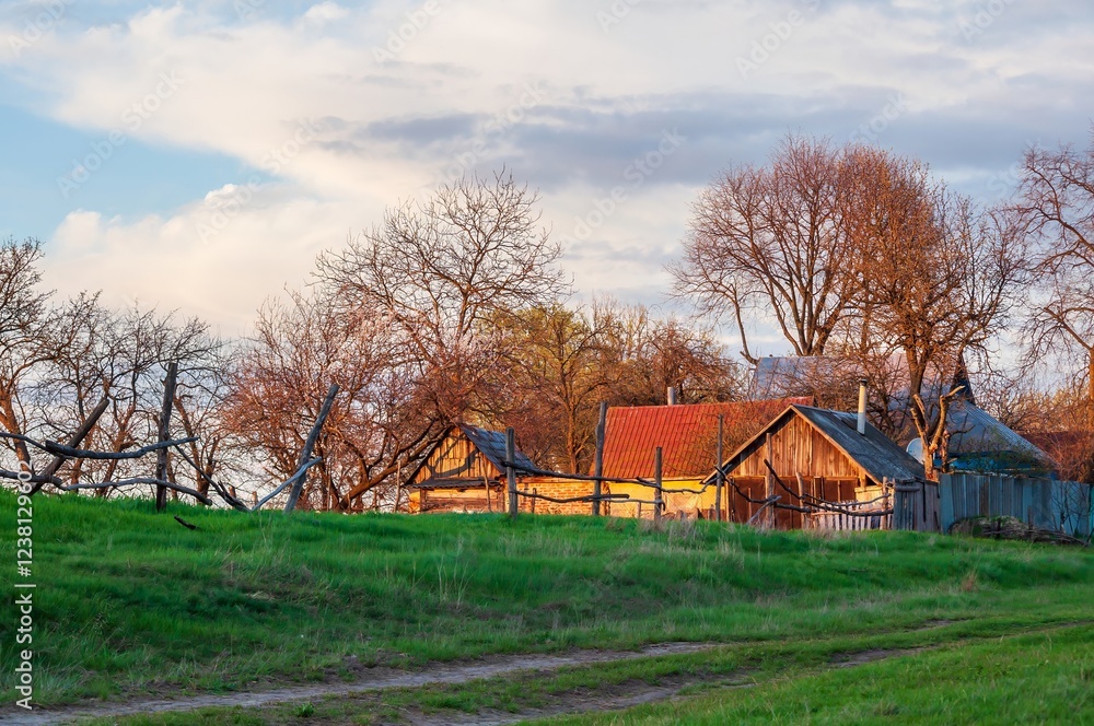 Charming rustic houses nestled on a green field under a serene, partly cloudy sky. Charming rustic houses nestled on a green field under a serene, partly cloudy sky.