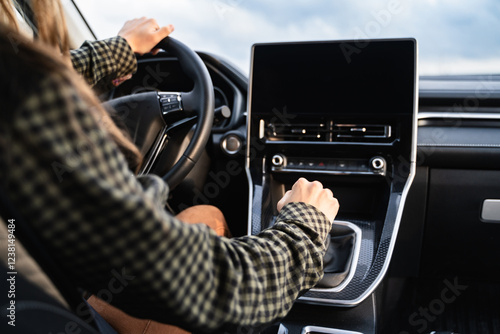 Fotografija An unrecognizable woman hand holding on the gearbox and changing speed in the car
