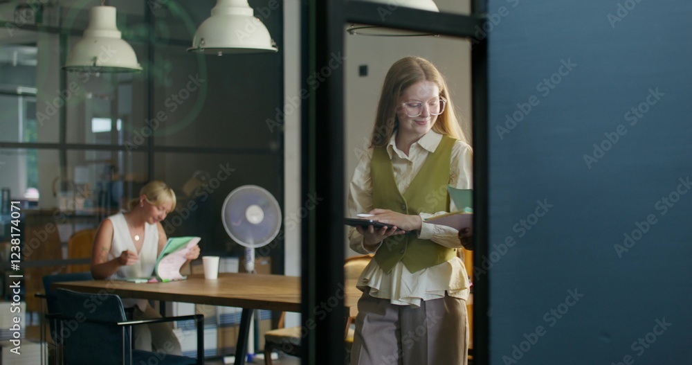 Two women are talking walking around the office. They use a tablet and read documents. Daylight Two women are talking walking around the office. They use a tablet and read documents. Daylight