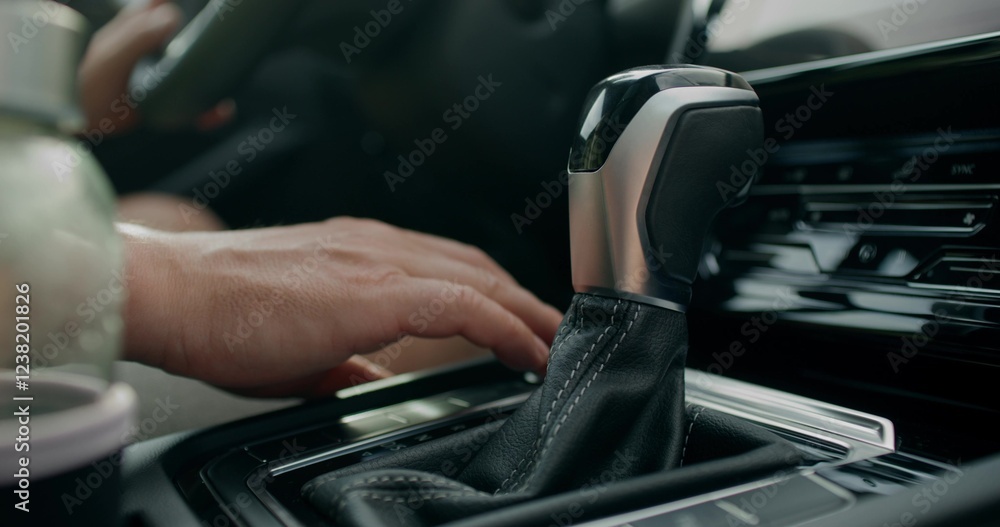 The man presses the keyless start button of the car and switches the gear. Close-up of his hands, an unrecognizable person. View from the car interior.