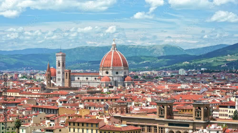 Panoramic view of Florence (Firenze), Italy, showcasing the city center with the Cathedral of Santa Maria del Fiore. Blue sky with clouds, rolling hills, and mountains in the background. Panoramic view of Florence (Firenze), Italy, showcasing the city center with the Cathedral of Santa Maria del Fiore. Blue sky with clouds, rolling hills, and mountains in the background.