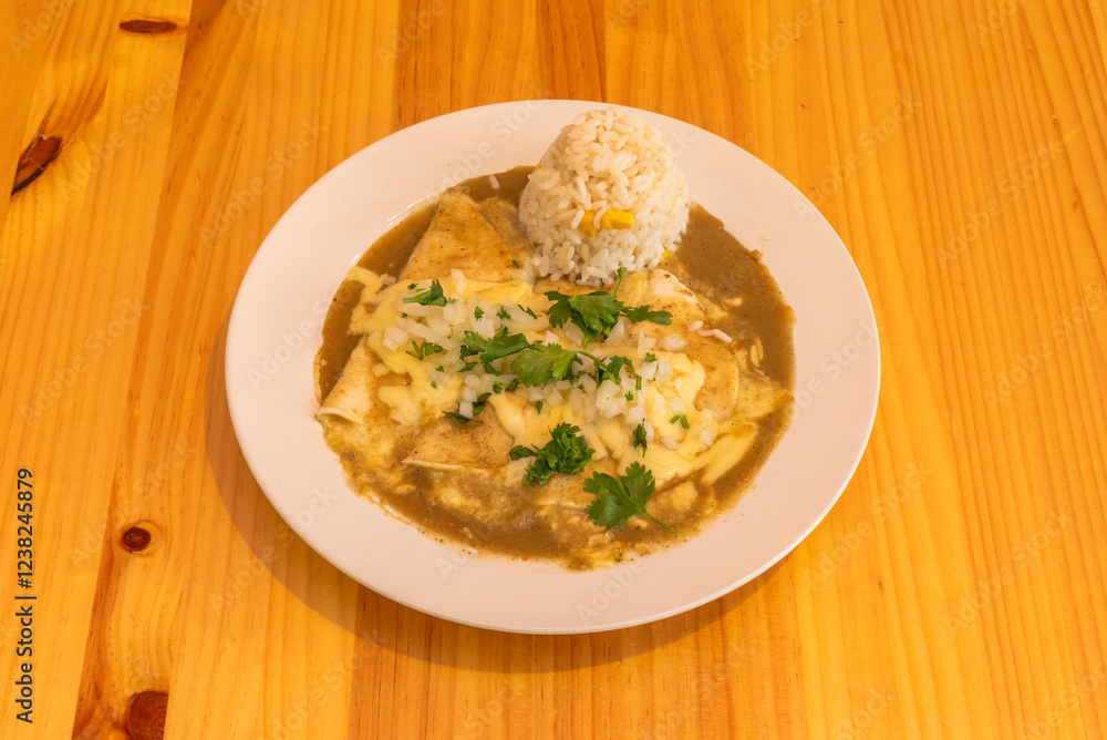 A plate of Mexican enchiladas with rice on a honey-colored pine table A plate of Mexican enchiladas with rice on a honey-colored pine table