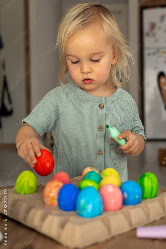 Obraz premium Colorful Easter egg decorating activity at home during spring holiday with a child