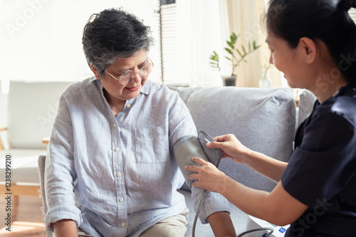Young Asian woman nurse take care senior woman at nursing home, checking blood pressure for observe health condition. Healthy senior home care or medical concept.