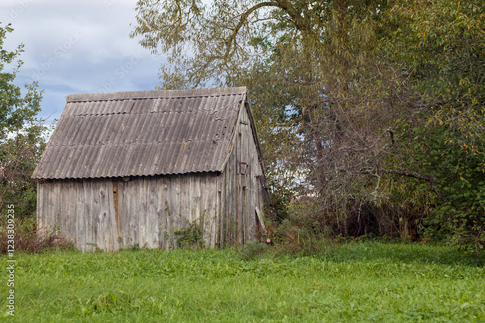 an old wooden hut in a grassy field with a dark roof.
an old wooden hut in a grassy field with a dark roof.