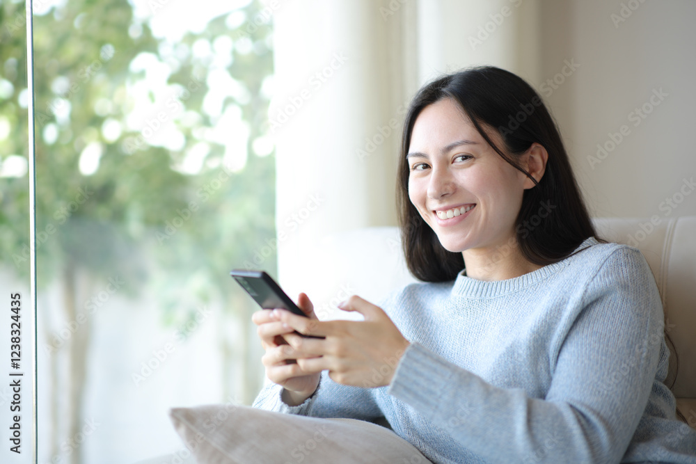 Happy asian woman using phone looking at camera at home Happy asian woman using phone looking at camera at home