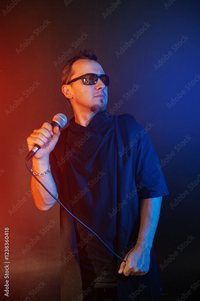 Rock singer with microphone and sunglasses against red and blue background Rock singer with microphone and sunglasses against red and blue background