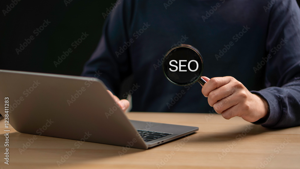 A businessman focuses on an SEO icon through a magnifying glass, analyzing search engine optimization to improve website ranking, boost traffic, and enhance visibility in search results.
