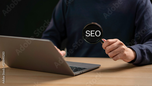 Obraz na płótnie A businessman focuses on an SEO icon through a magnifying glass, analyzing search engine optimization to improve website ranking, boost traffic, and enhance visibility in search results. w salonie