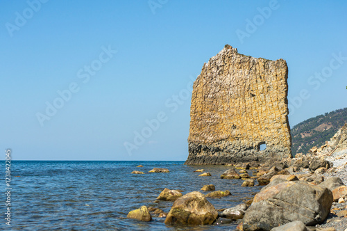 Coastal scene in Gelendzhik featuring rocky shoreline with scattered stones. Prominent rock 