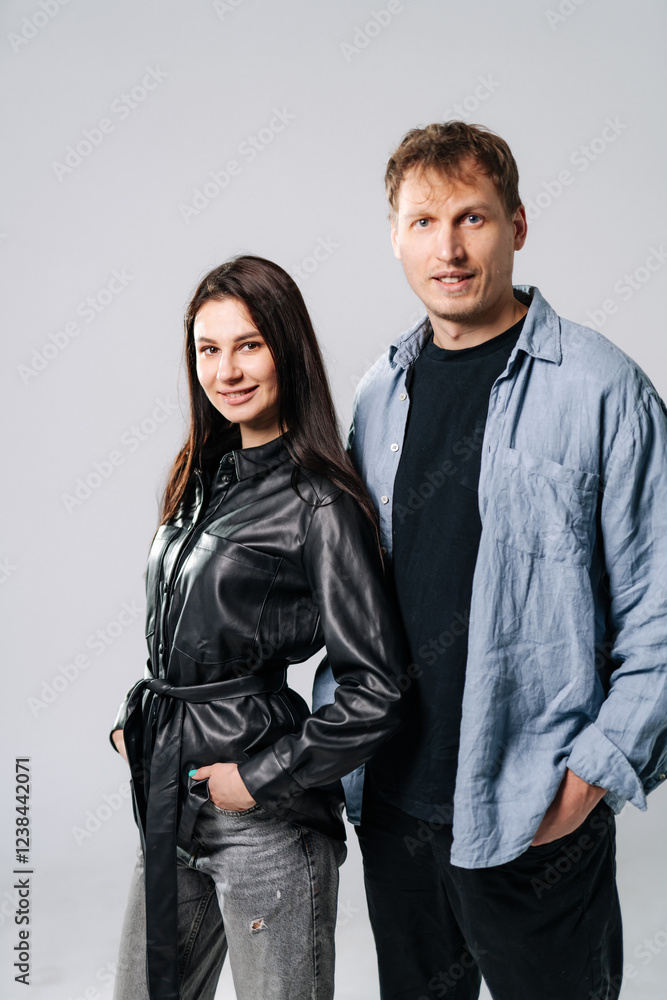 Couple confidently poses casually. A couple stands side by side, smiling, wearing stylish casual clothes in a neutral studio setting. Couple confidently poses casually. A couple stands side by side, smiling, wearing stylish casual clothes in a neutral studio setting.