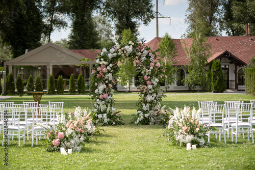 Wedding ceremony. Very beautiful and stylish wedding arch, decorated with various fresh flowers, standing in the garden.