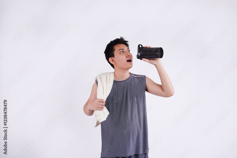 Full body image of an Asian guy wearing gym clothes, using a phone and posing on a white background Full body image of an Asian guy wearing gym clothes, using a phone and posing on a white background