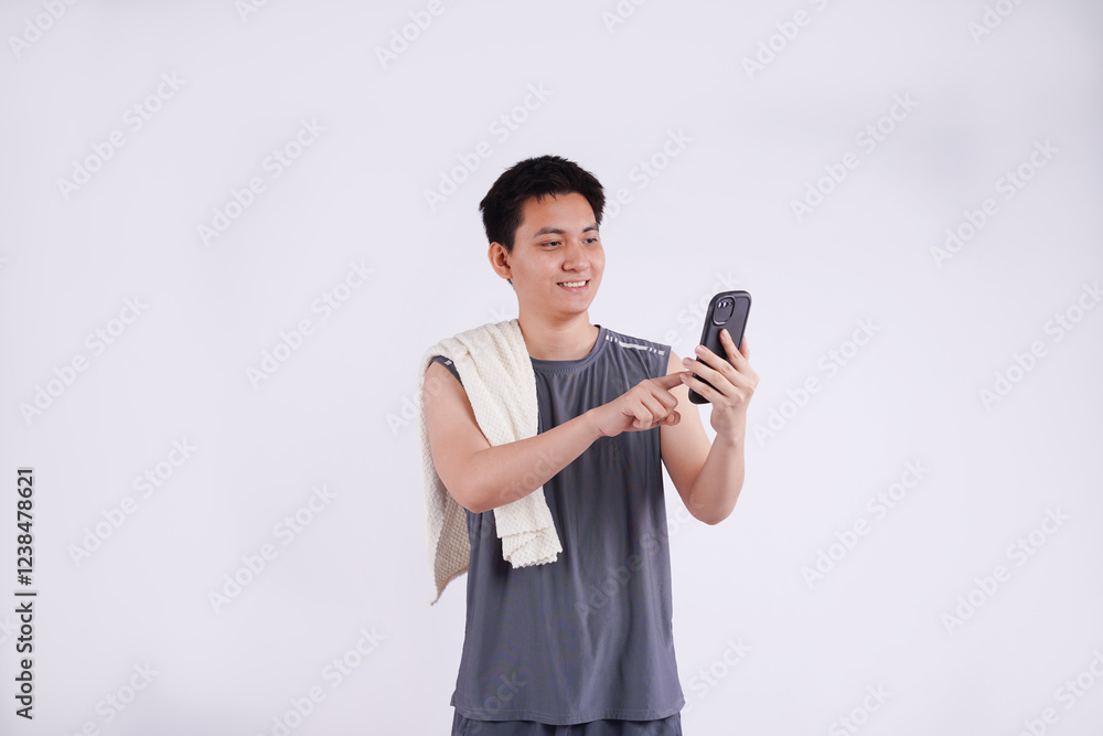 Full body image of an Asian guy wearing gym clothes, using a phone and posing on a white background Full body image of an Asian guy wearing gym clothes, using a phone and posing on a white background