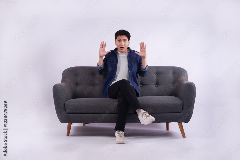 Full body image of young Asian man posing on sofa on white background Full body image of young Asian man posing on sofa on white background