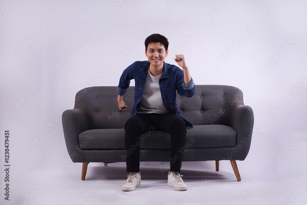 Full body image of young Asian man posing on sofa on white background Full body image of young Asian man posing on sofa on white background