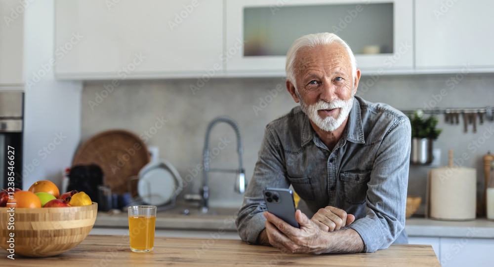 Portrait of senior men at home using smart phone. Senior man drinking morning orange juice at his domestic kitchen and using his phone. Portrait of senior men at home using smart phone. Senior man drinking morning orange juice at his domestic kitchen and using his phone.