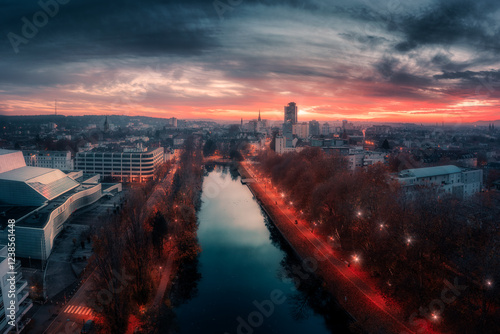 Captivating aerial view of Mulhouse at sunset, with illuminated streets and a river reflecting the last light of the day. A perfect blend of modern and historical cityscape