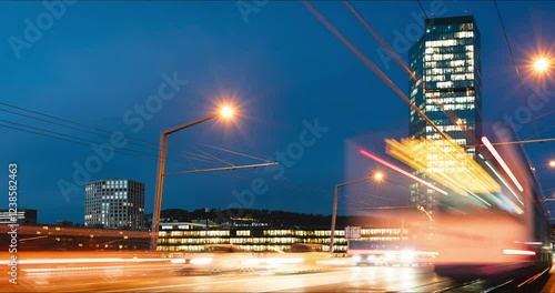 27-01-2025 Zurich, Switzerland. Time lapse of cars and public transport on a busy Hardbrucke bridge at night. Bridge side view, famous Prim Tower skyscraper building in the background photo