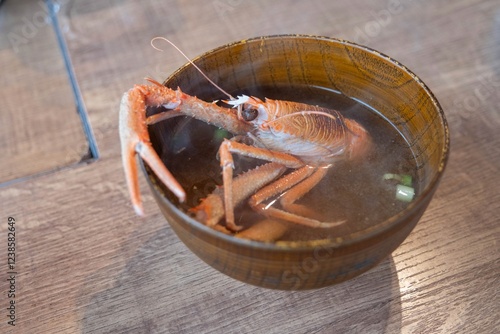 A red crab sitting in a steaming bowl of miso soup with thick broth at a restaurant in Japan.  photo