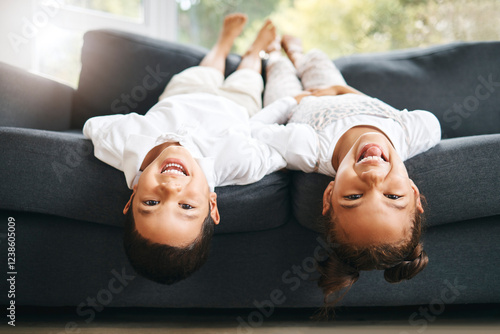 Portrait, upside down and happy kids on couch laughing at funny joke with joy or games in family home. Girl, silly boy and playful children siblings bonding on sofa playing together in house to relax