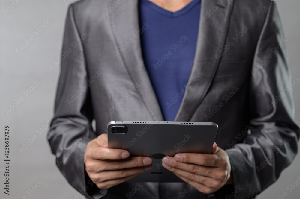 Business Professional in Suit Holding Tablet Device in Modern Setting Business Professional in Suit Holding Tablet Device in Modern Setting