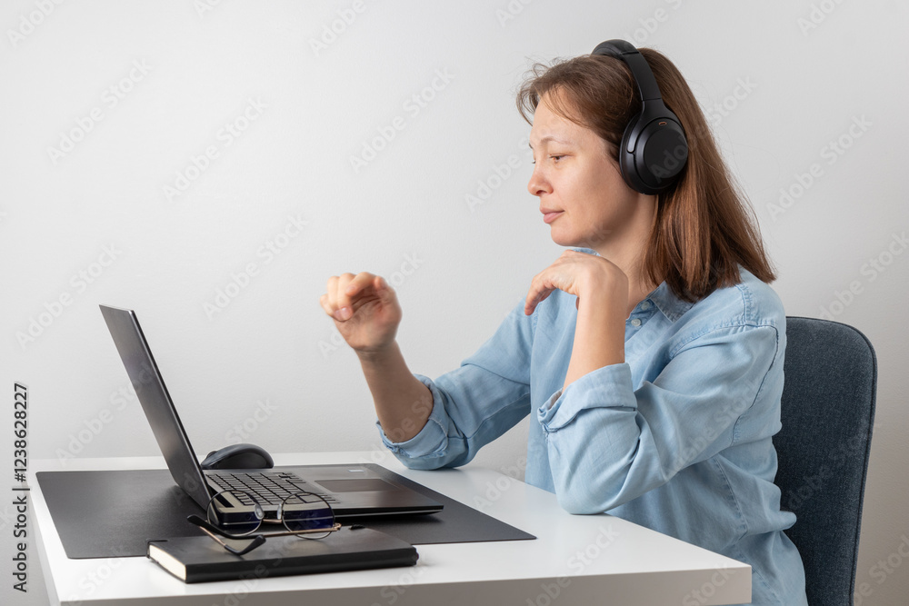 A calm nice woman with headphones using laptop, looking at PC screen, remote hardworking freelancer works from home. Correct posture A calm nice woman with headphones using laptop, looking at PC screen, remote hardworking freelancer works from home. Correct posture