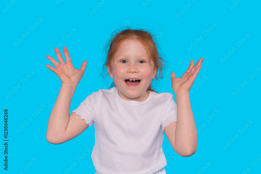 Young girl expresses joy in front of bright blue background while raising hands Young girl expresses joy in front of bright blue background while raising hands