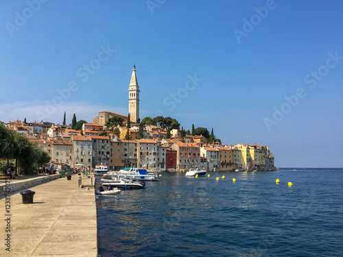 A View of Rovinj's Colorful Harbor.  The colorful buildings of the town climb up a hill, culminating in the impressive bell tower of St. Euphemia's Church.  photo