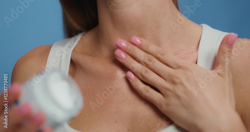 Konstfotografi A woman applies a cosmetic cream to her neck while standing on a studio background