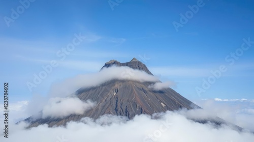 The summit of a dormant volcano towers above a shroud of mist, its craggy shape a testament to geological time, erosion, landscape, geology