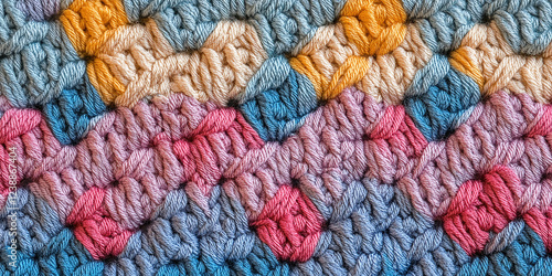 Close-up of intricately woven, colorful crochet fabric featuring a zigzag pattern of soft, vibrant threads in pastel and bold tones.