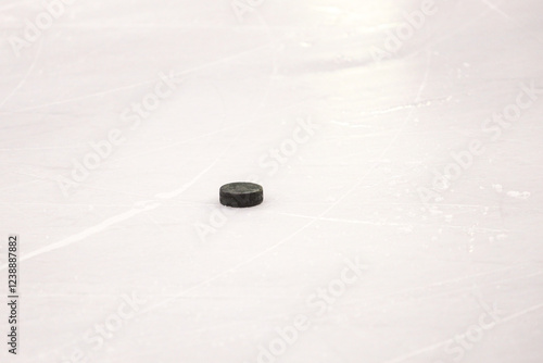 Photography Old Black Single puck laying on ice hockey rink arena.