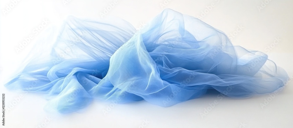 Obraz premium Soft translucent blue tulle fabric draped artistically with flowing folds and textures on a white background with Copy Space