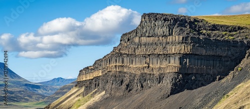 Layered volcanic rock formation in Iceland under blue sky with clouds showcasing unique geological structures and textures Copy Space photo