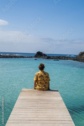 Tourist relaxing on a wooden pier in fuerteventura, canary islands, spain